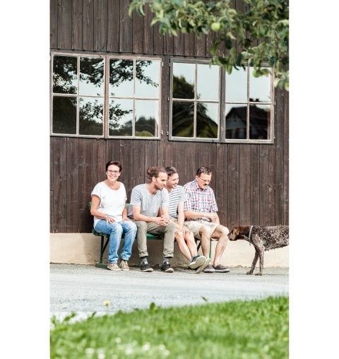 Die Familie Schalk mit Hund sitzend vor einer Stufe im Außenbereich
