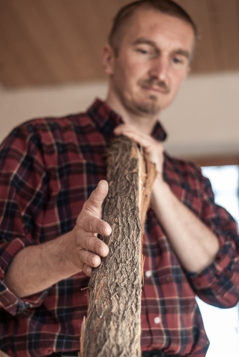 Mann hält ein Stück Holz in der Hand