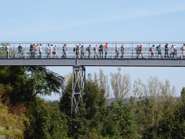 Eine Gruppe von Personen die über die ehemalige Verbindungsbrücke zu den Tabakwerken Fürstenfeld geht