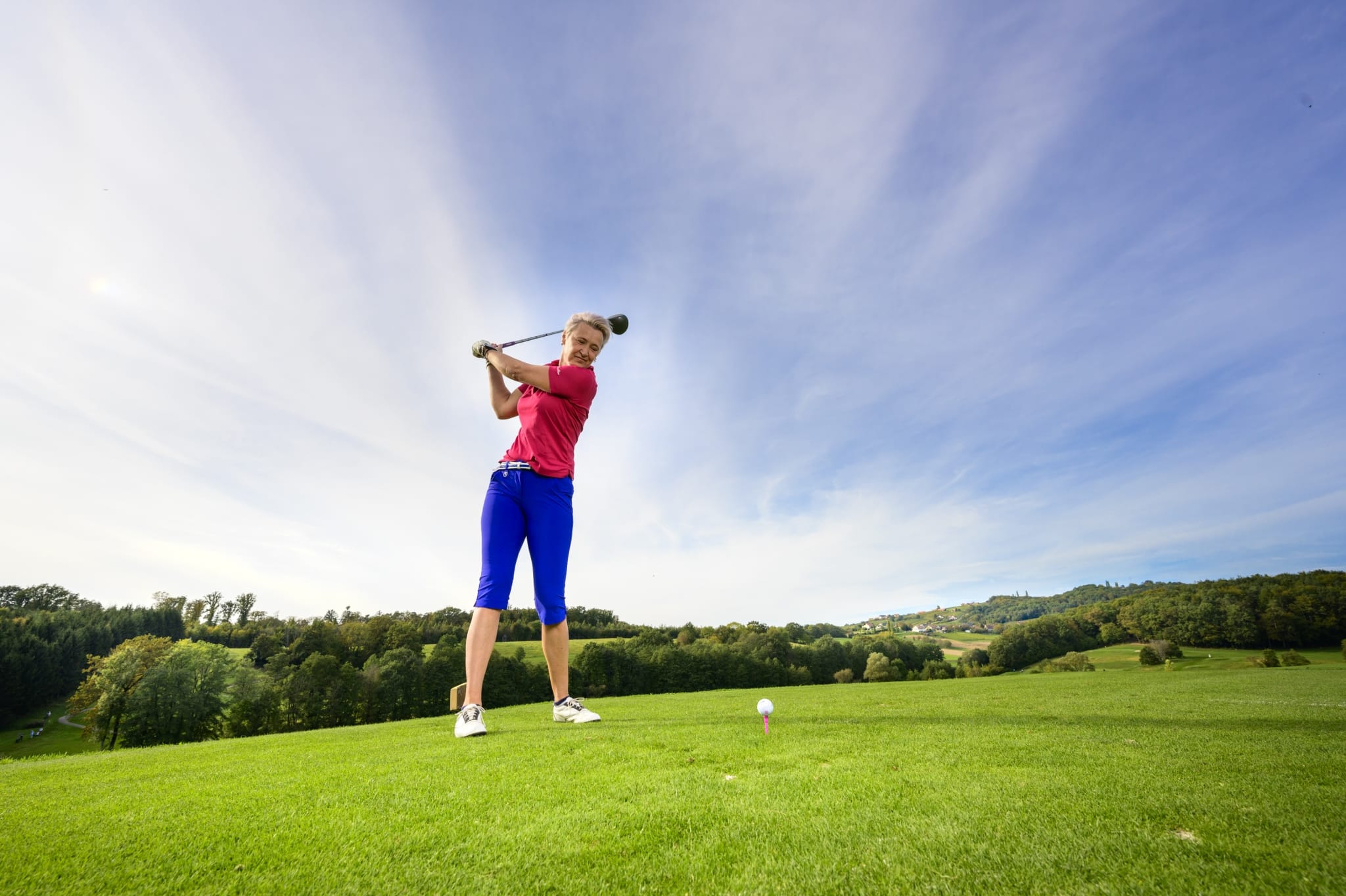 Frau schwingt Golfschläger auf Golfplatz