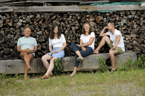 Familie Ploder auf einem Baumstamm vor einem Holzstoß
