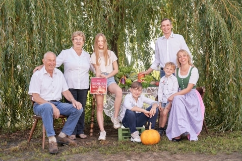 Eine Familie vor einem Baum mit einer Gemüsekiste im Hintergrund