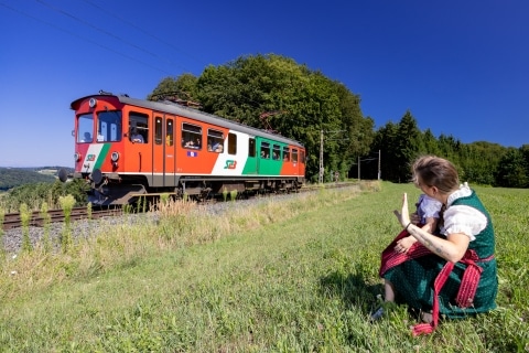 Zug fährt durch die grüne Landschaft bei blauem Himmel