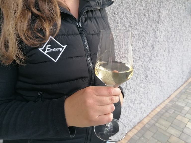 Eine Frau, die ein Glas Weißwein in der Hand hält