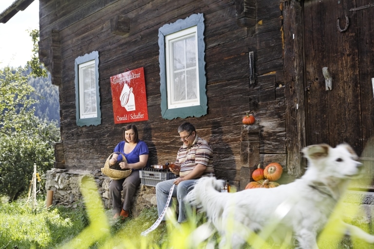 Ein Mann und eine Frau vor einem Holzhaus die Produkte mit Etiketten versehen