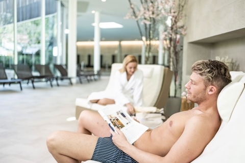 Ein Mann liest in einem Magazin auf der Entspannungsliege