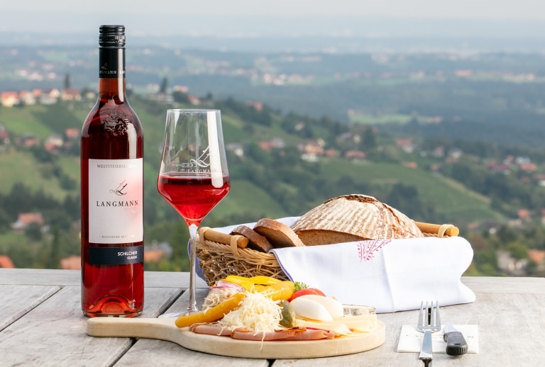 Eine Brettljause im Hintergrund das Panorama rund um das Weingut Langmann