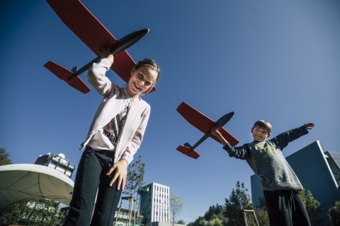 Kinder die mit Flugzeugen im Innenhof spielen