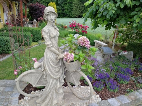 Eine Gartenstatue mit blühenden Pflanzen