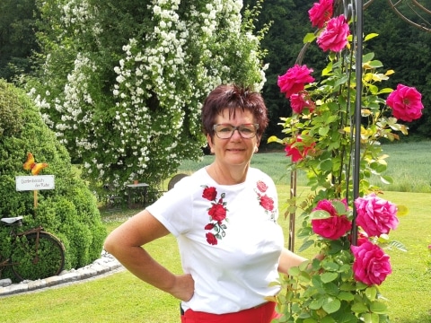 Christine Neuhold neben einem blühenden Rosenstrauch