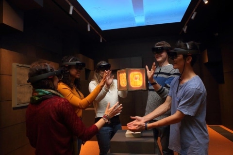 Jugendliche mit VR Brillen die ein Hologramm bestaunen