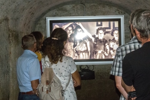 Eine Personengruppe die einen Film in einem unterirdischen Bunker ansieht