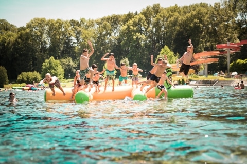 Kinder und Jugendliche die von einer Luftmatratze im Freibad Fürstenfeld ins Wasser springen