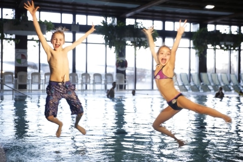 Kinder die ins Wasser im Hallenbad Hartberg springen