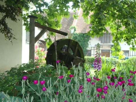 Ein wasserbetriebenes hölzernes Mühlenrad, dass in einem Garten steht