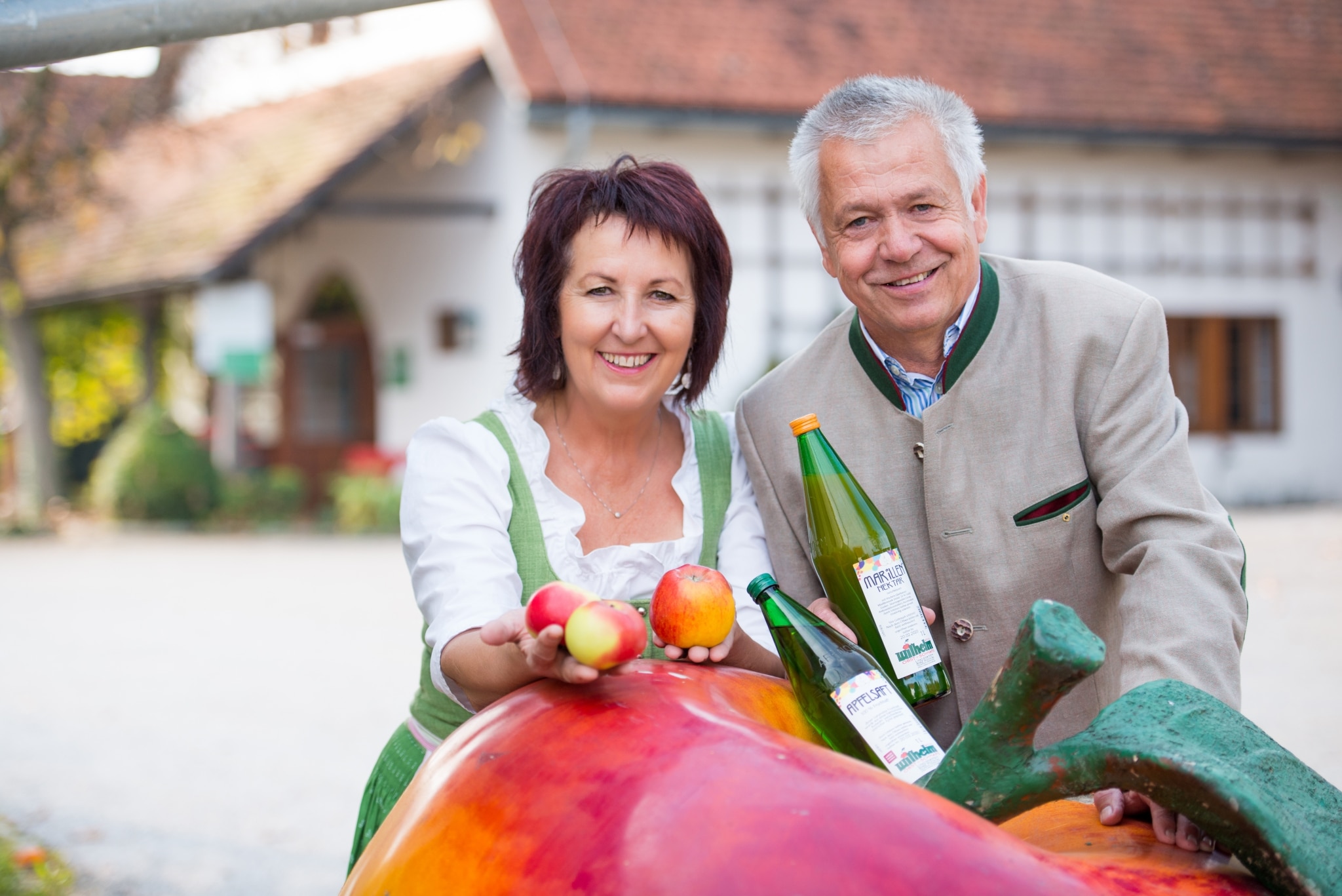 Ein Mann und eine Frau vor einem großen Apfel mit hauseigenen Produkten