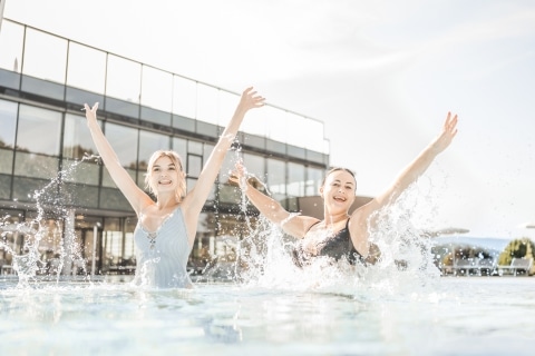 Zwei junge Frauen hüfen im Wasser und lächeln in die Kamera