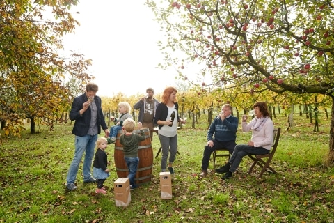 Familie Sorger im Garten unter einem Apfelbaum beim Verkosten der eigenen Produkte