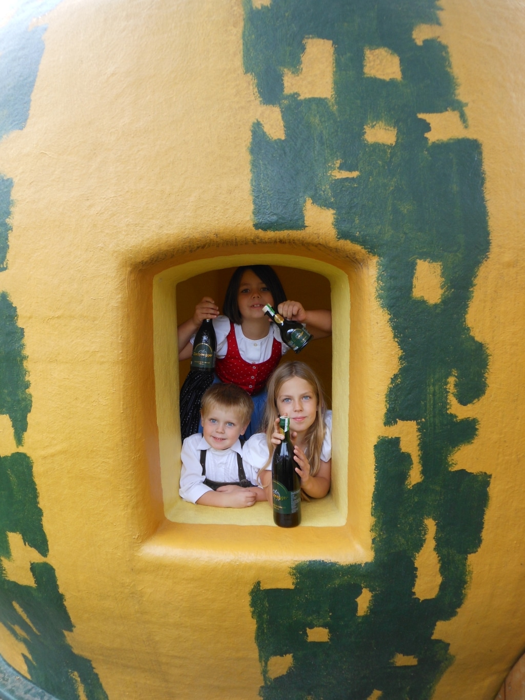 Drei Kinder die aus einem Spielhaus in Kürbisform schauen