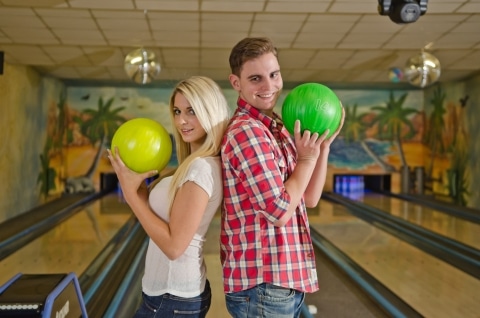 Ein Mann und eine Frau, Rücken an Rücken vor der Bowlingbahn