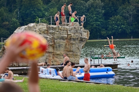 Personen die vom Sprungfelsen in den See springen