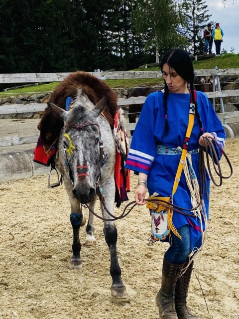 Eine Frau in Stammeskleidung führt ein Pferd