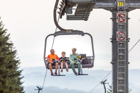 Eine Familie fährt mit dem Sessellift den Berg hinauf