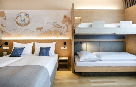 Sie sehen ein Familienzimmer FF4 mit Etagenbetten und Doppelbett im JUFA Hotel Weiz. Der Ort für kinderfreundlichen und erlebnisreichen Urlaub für die ganze Familie.