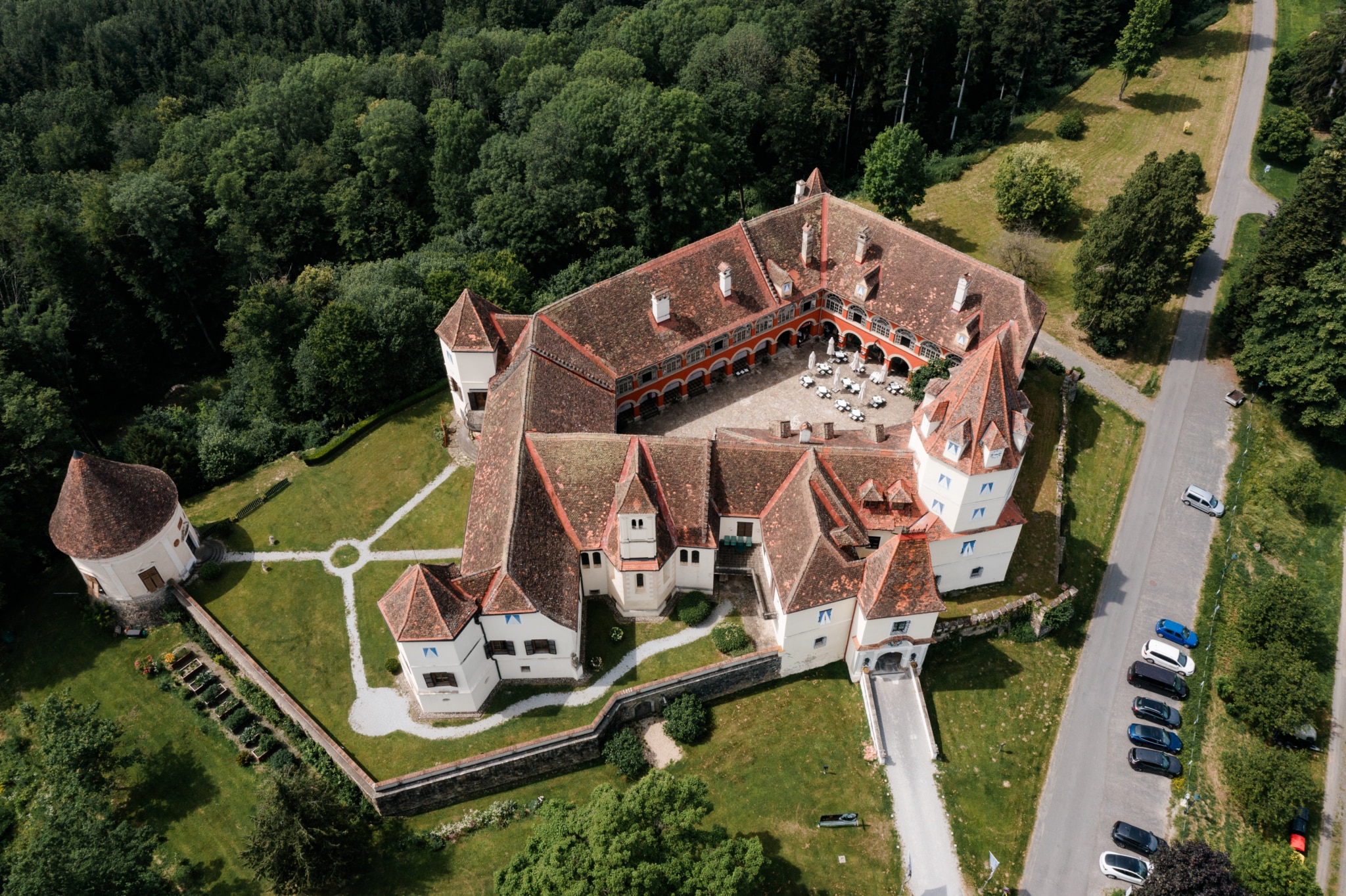 Schloss Kornberg von Oben, man sieht den Innenhof mit Tischen und Bänken und Sonnenschirmen