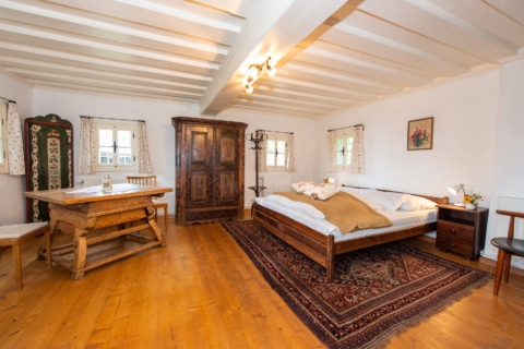 Ein Schlafzimmer mit Holzgarnitur. Das Bett steht auf einem gemusterten Teppich.