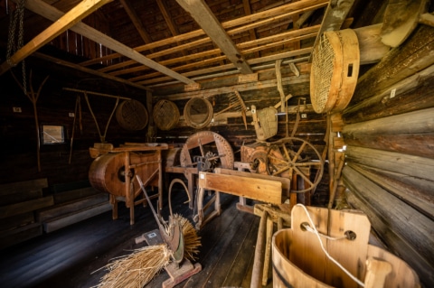 Zu sehen ist das Innere von einem Haus in dem viele altertümliche Werkzeuge aus Holz stehen.